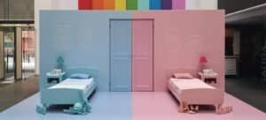 Instalación artística de una habitación infantil dividida por la mitad. El lado izquierdo es azul con juguetes tradicionalmente masculinos y el derecho es rosa con juguetes femeninos, simbolizando los estereotipos de género.