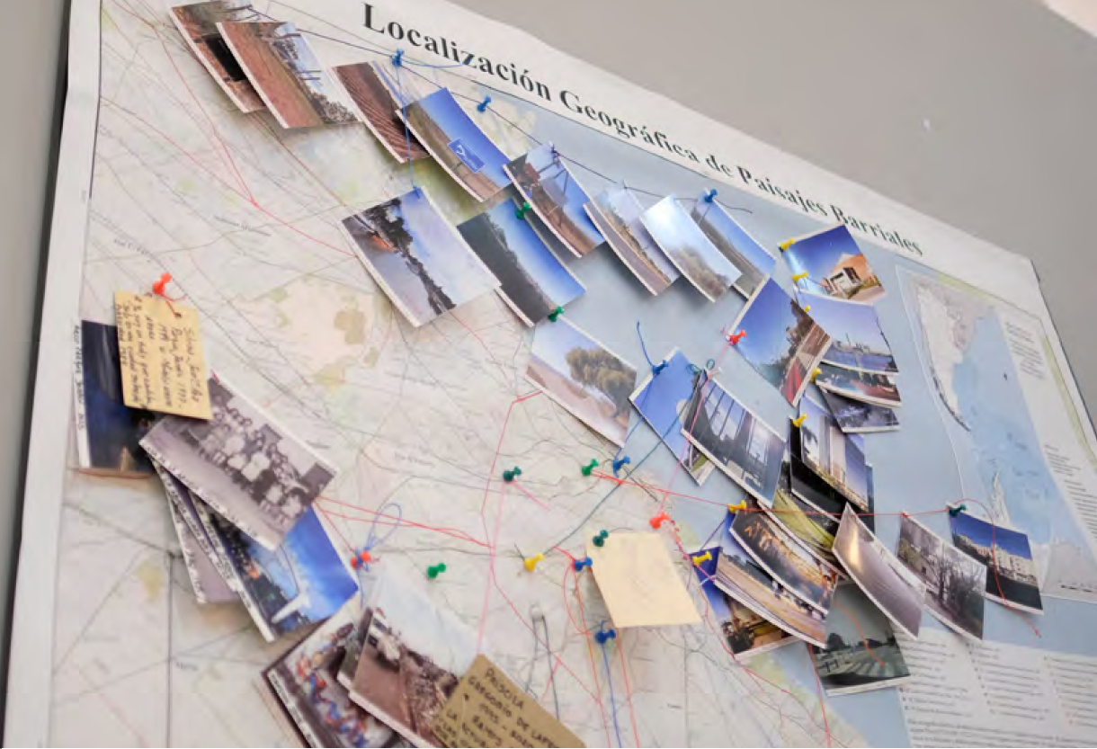 Mapa de Argentina con fotos de paisajes barriales sujetas con chinchetas, representando la geografía en 40 años de democracia.