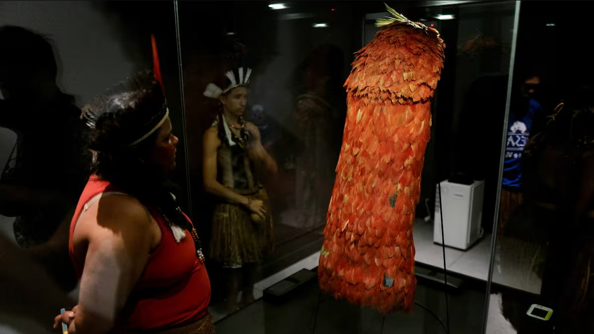 Capa indígena de plumas rojas en exhibición, parte de una colección que regresa a Brasil tras siglos en Dinamarca.