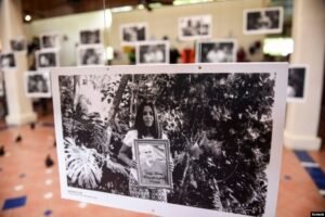 Fotografía en blanco y negro colgada en una exposición, mostrando a una mujer sosteniendo el retrato de un familiar desaparecido.